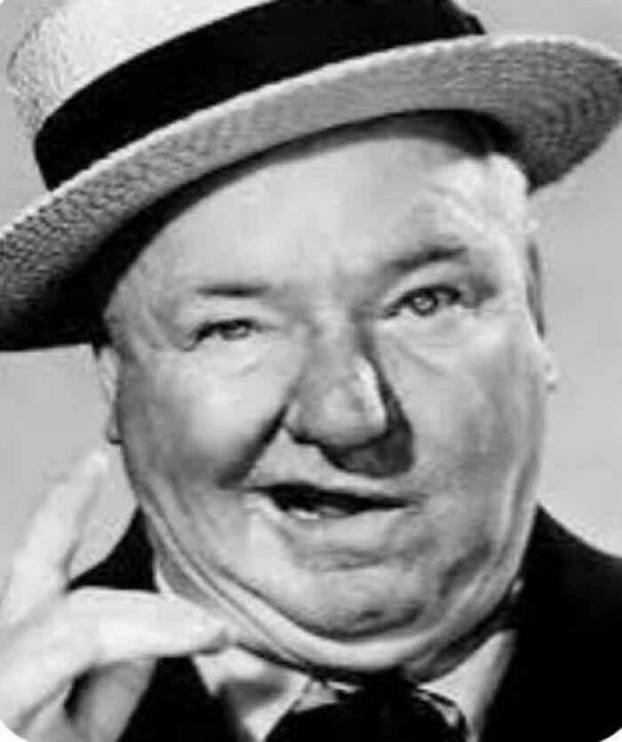 Black and white photo of a vintage man in a hat making a hand gesture that may make people feel very old.