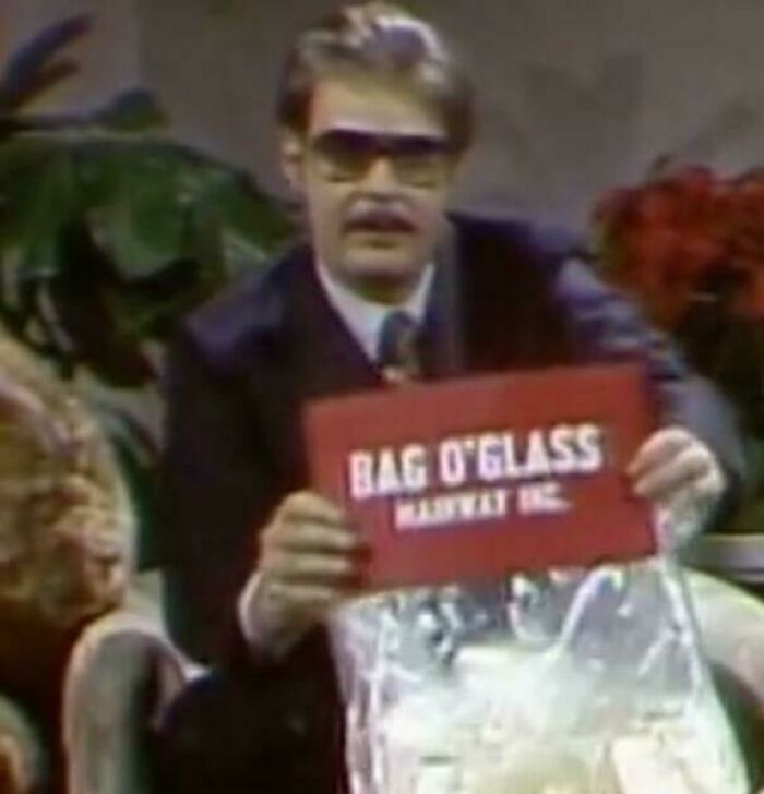 Man in vintage suit and sunglasses holding a classic bag of glass brand, evoking nostalgia for people who recognize them.