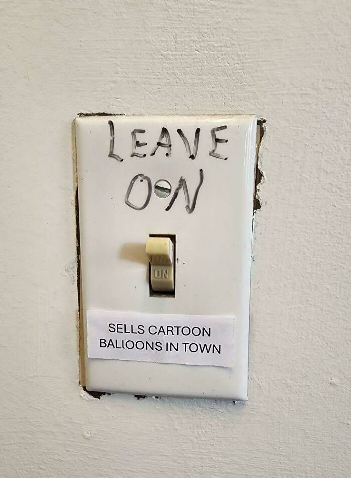 Old-fashioned light switch with handwritten note saying leave on and a paper label about cartoon balloons in town.