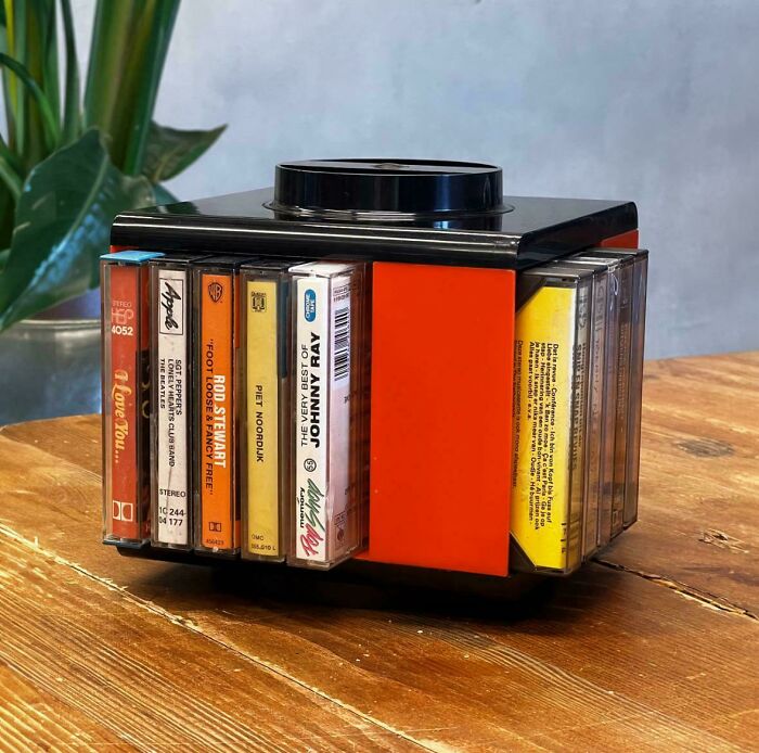 Rotating cassette tape holder with vintage music tapes on a wooden table, a nostalgic item that makes people feel very old.