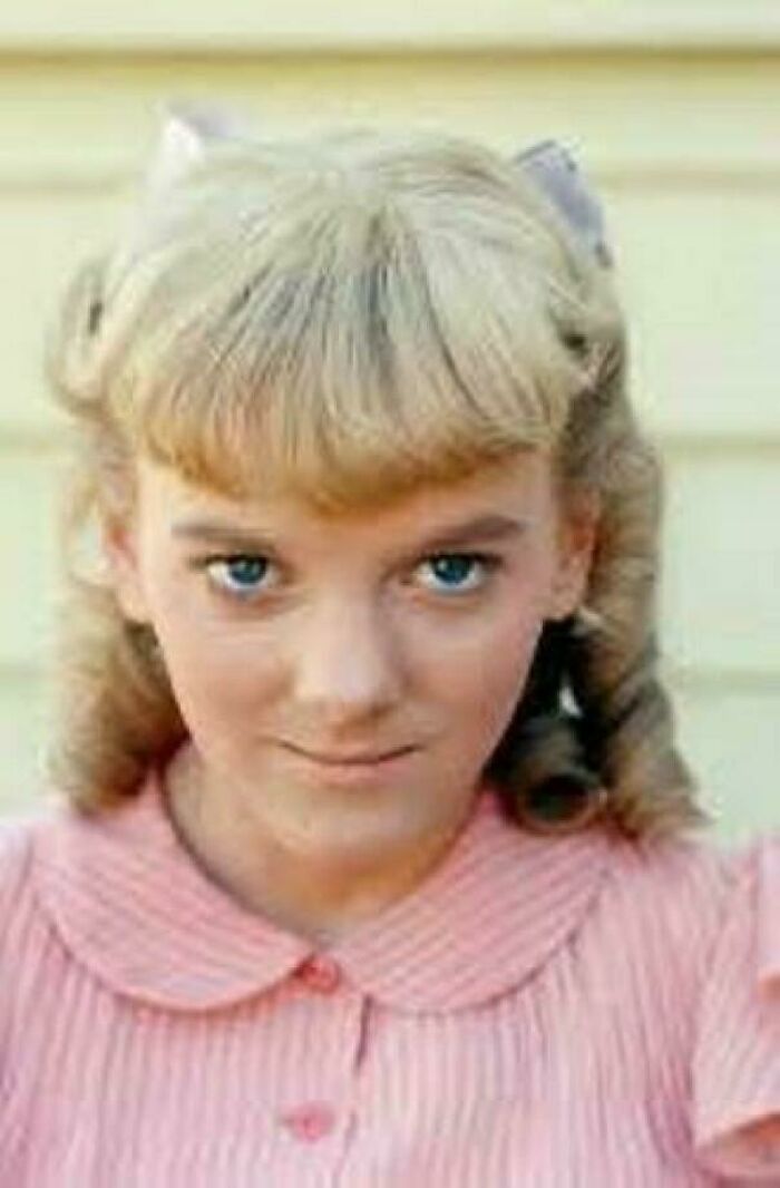 Young girl with curled blonde hair and a pink dress, a nostalgic image from things that make people feel very old.