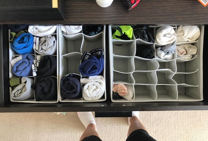 Drawer with multiple fabric organizers neatly storing rolled clothes, showcasing clever products to organize chaotic corners of a home.