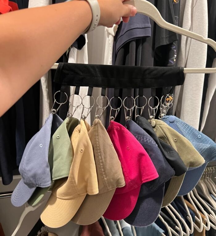 Hand holding a clever product for organizing hats on hangers, optimizing chaotic home storage spaces efficiently.