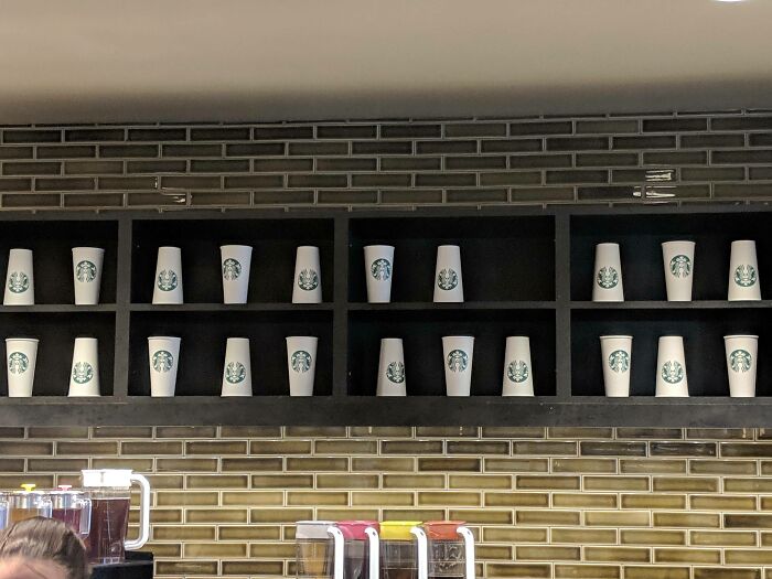 Starbucks cups arranged on shelves in an imperfect pattern, showcasing things that annoy people with OCD tendencies.