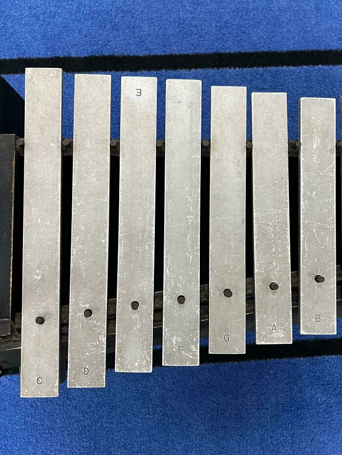 Metal keyboard bars arranged unevenly on a blue carpet, showing imperfect alignment that may annoy people with OCD.