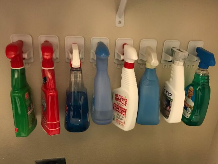 Cleaning spray bottles hanging on hooks, demonstrating clever products to organize chaotic corners of a home.