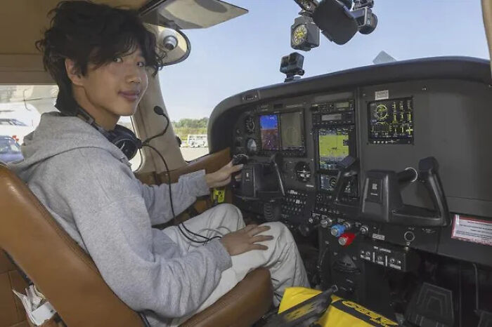 Young person in pilot seat inside small aircraft cockpit, wearing headset, part of online group sharing interesting facts and pics