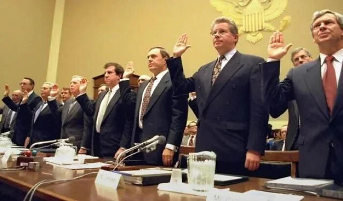 Group of men in suits raising hands during a formal hearing, featured in an online group sharing interesting facts.