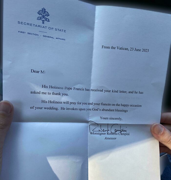 Letter from the Vatican sharing blessings and interesting facts about a wedding, held by two hands in sunlight.