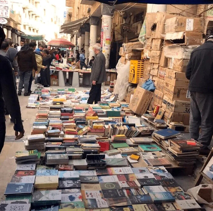 Outdoor market with piles of books and cardboard boxes, showing interesting facts and pics shared by an online group.