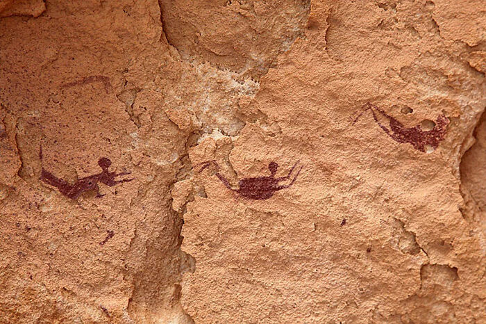 Ancient cave paintings of human figures and animals on a rocky surface shared by an online group with interesting facts.