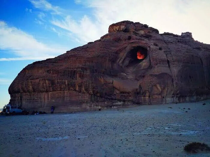 Natural rock formation resembling an eye with bright orange light inside, shared by an online group featuring interesting facts.
