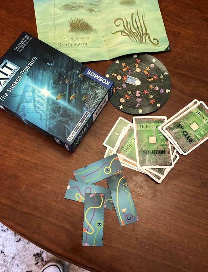 Board game setup on wooden table with puzzle cards, spinner, and map, showcasing fun hobbies to try offline.