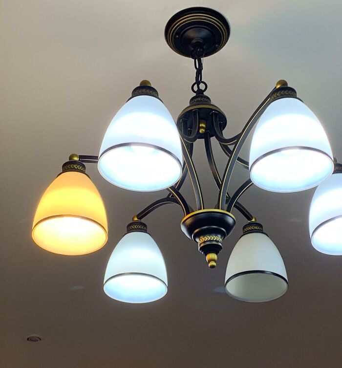 Chandelier with multiple light bulbs, one bulb emits different color, showing imperfect things that annoy.