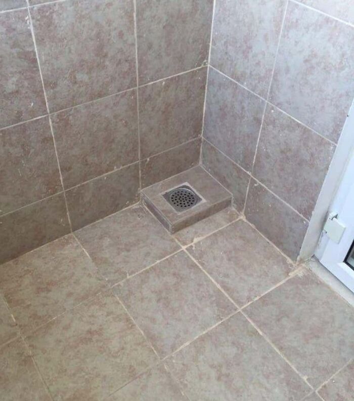Bathroom floor tiles with a poorly aligned drain setup, a common imperfect thing that annoys people with OCD.