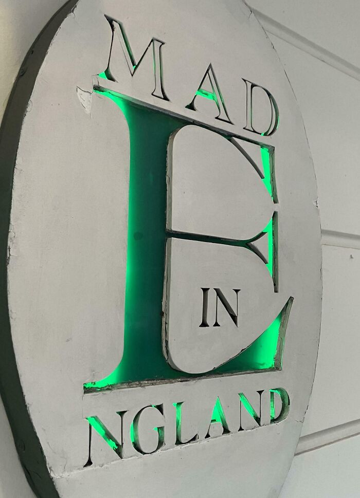 White engraved wooden plaque with chipped edges and green backlight, displaying imperfect lettering that may annoy people with OCD.