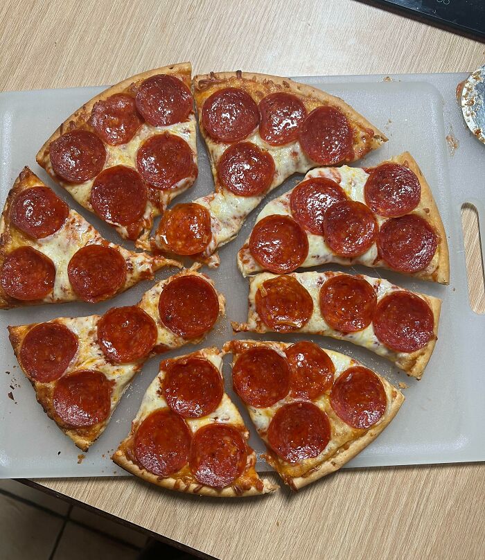 Pepperoni pizza with uneven slice sizes on a cutting board, showing imperfect things that annoy people with OCD.