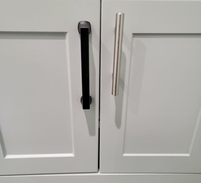 Mismatched cabinet handles on white cupboards showing imperfect details that may annoy people with OCD.