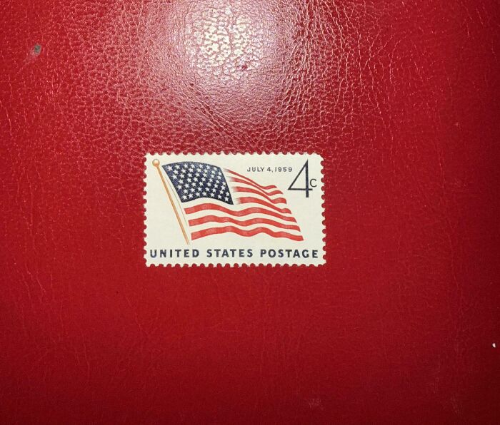 Vintage 1959 United States postage stamp featuring the American flag on a textured red background, capturing 1950s life.
