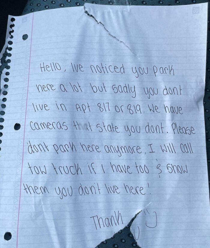 Handwritten neighbor’s note warning about unauthorized parking and mentioning cameras and tow truck threats in an apartment complex.