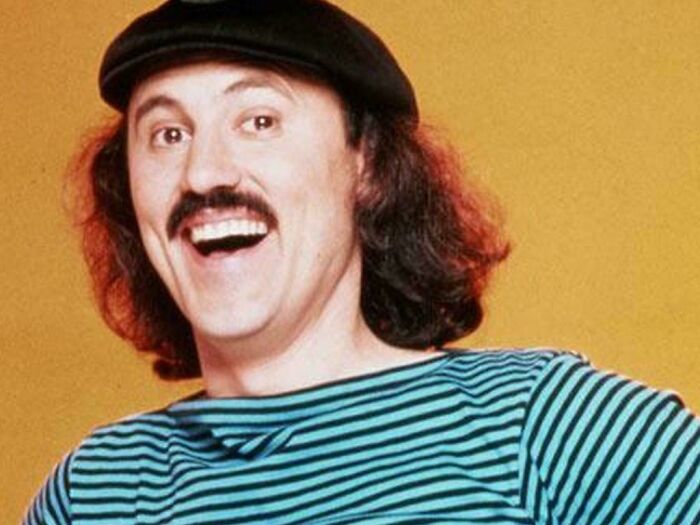 Man with mustache and long hair wearing a striped shirt and beret, evoking nostalgic memories of old age and past decades