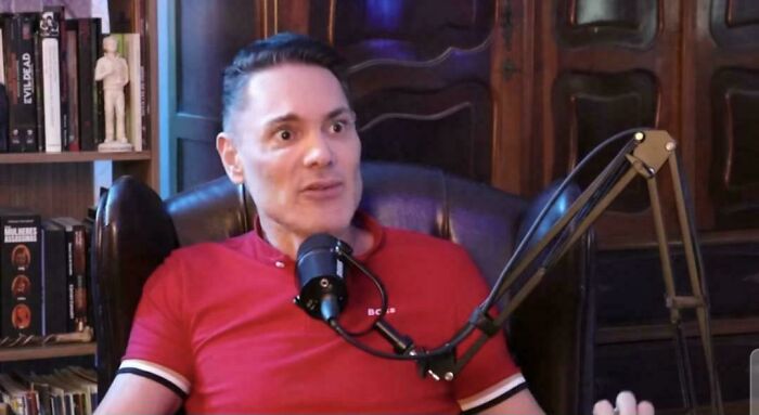 Man in a red shirt speaking into a microphone during a discussion about worst brides, grooms, and wedding guests.