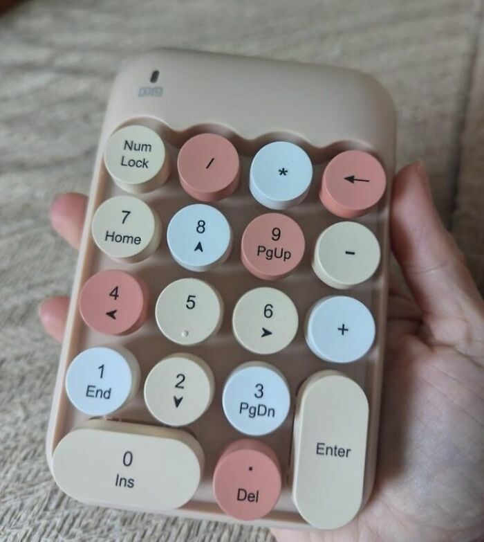 Hand holding a retro-style numeric keypad with pastel-colored round and oval keys, a coolness-worthy tech accessory.