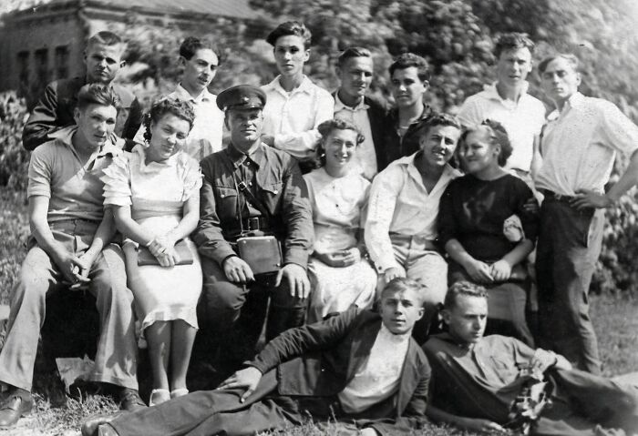 Group of students and a military officer posing outdoors near a school during World War II, capturing a historic moment worldwide.