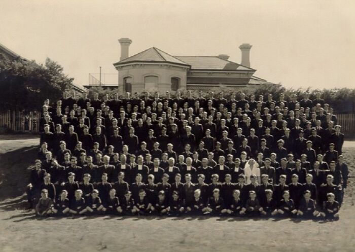 Large group of students and staff posing for a formal school photo outdoors during World War II era.