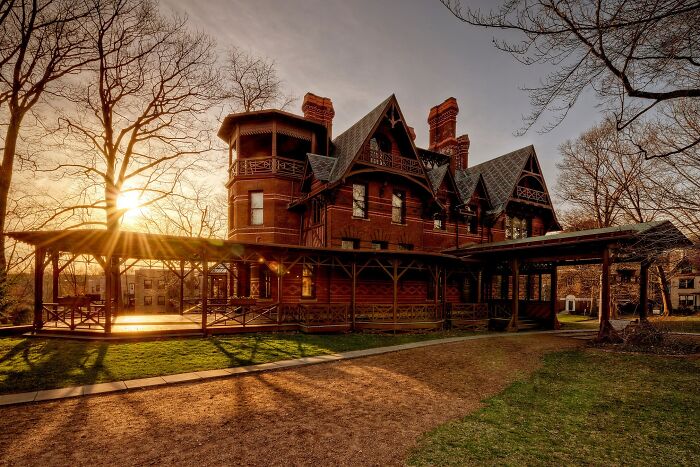 Historic home with intricate woodwork and steep gabled roofs, showcasing America’s architectural heritage at sunset.