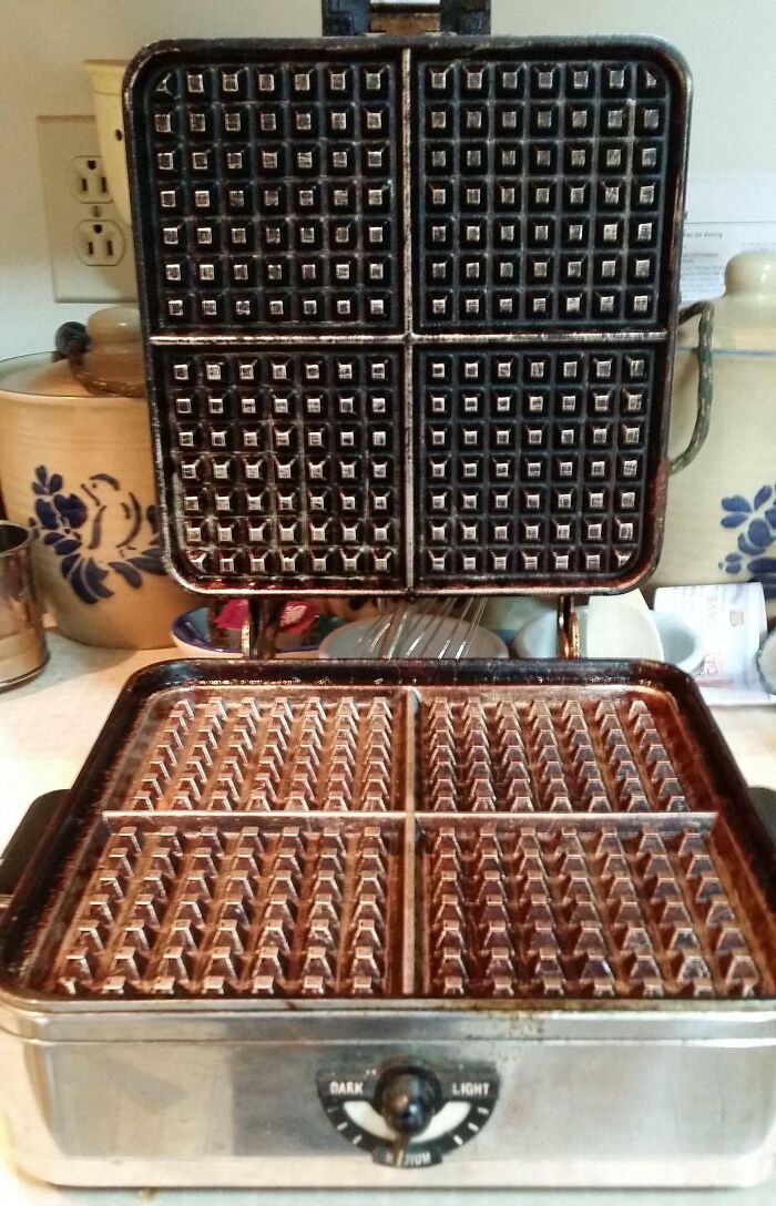 Vintage waffle iron with a metal exterior and four square grids, reflecting life and kitchen appliances from the 1950s era.