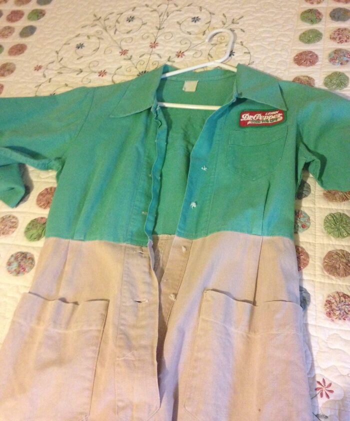 Vintage 1950s Dr Pepper work uniform in green and beige laid out on a quilt with circular patterns.