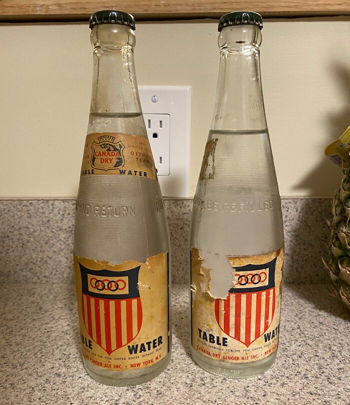 Two vintage Canada Dry table water bottles with worn 1950s labels on a kitchen countertop.