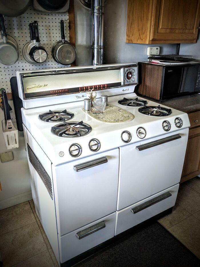 Vintage 1950s white gas stove in a retro kitchen with hanging pots and wooden cabinets, capturing essence of life in the 1950s.