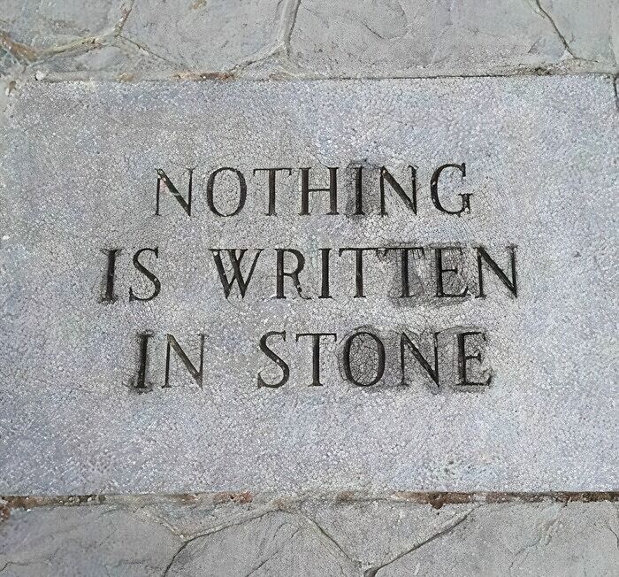 Stone plaque with the awkward phrase nothing is written in stone carved into its surface, illustrating awkward photos theme.