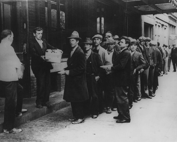 Men in a long line receiving food during the Great Depression, a somber photo from history showing hardship and poverty.