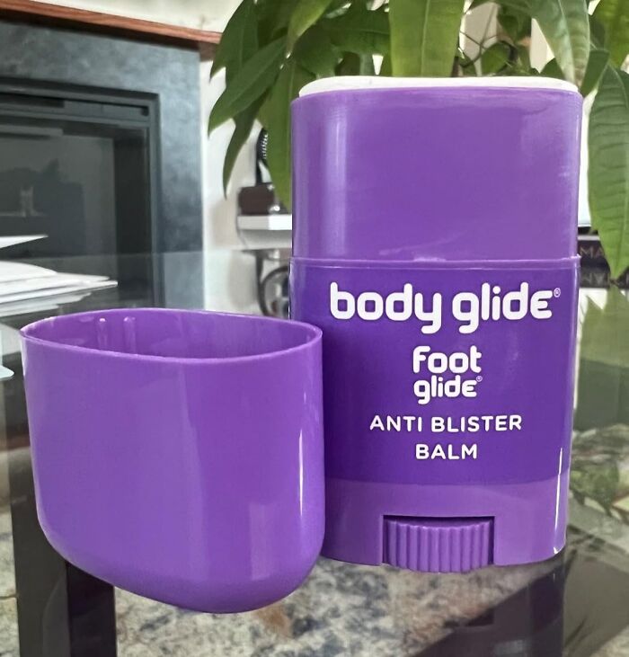 Purple Body Glide foot glide anti blister balm stick on a glass table with a plant in the background, budget problem solvers under 15.