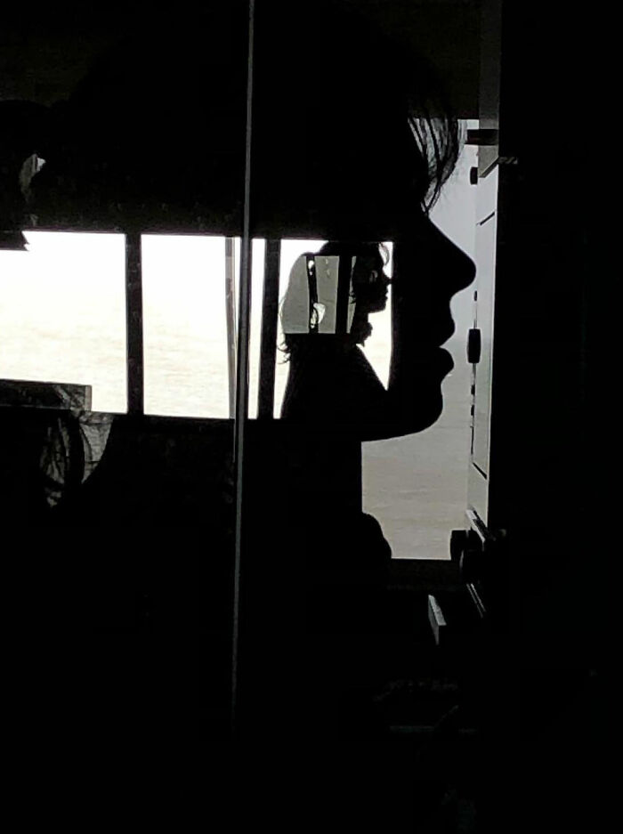 Silhouette of a person's profile with a smaller reflection of a photographer inside, a funny accidental image captured perfectly.