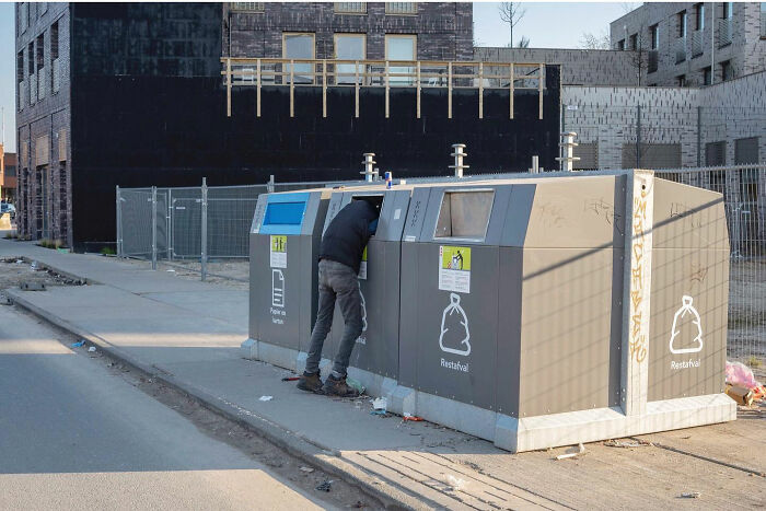 Man accidentally caught looking inside trash bin in funny accidental image taken at the right time by street photographer
