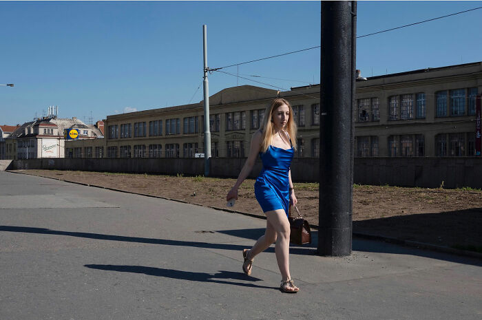 Young woman in a blue dress walking on an empty street, captured in a funny accidental image by a street photographer.