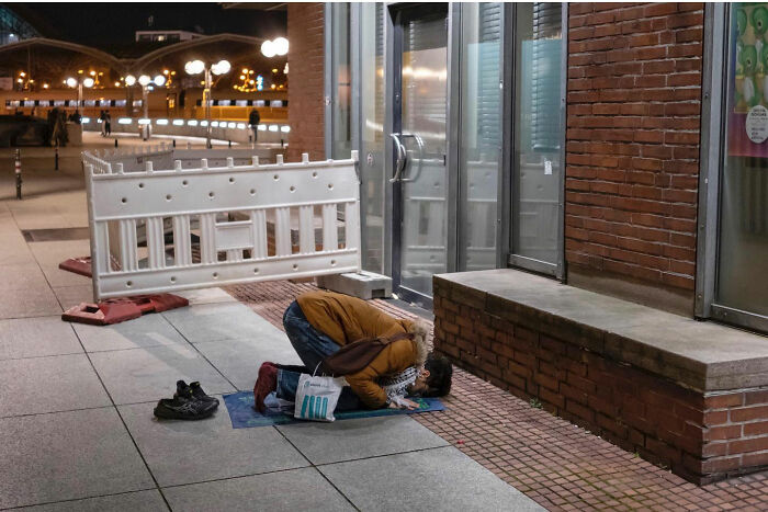 Person kneeling on sidewalk in funny accidental image taken at the right time and place by street photographer