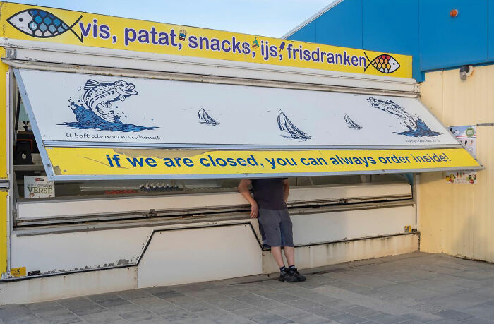 Person accidentally hidden behind a street vendor shutter in a funny accidental image captured at the right time and place