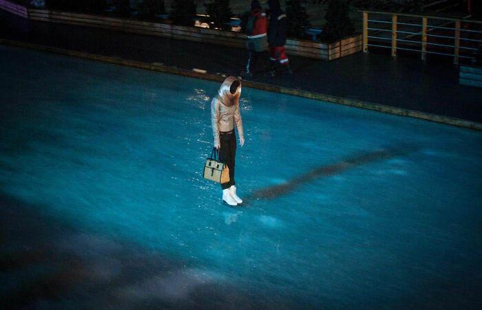 Woman appearing to float above icy street, holding a bag, captured in a funny accidental image by street photographer.
