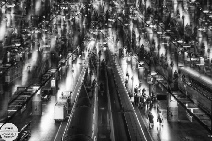Black and white street photo capturing motion and crowds at a busy train station, showcasing incredible street photography.