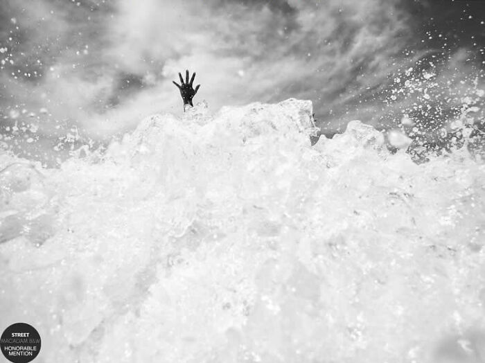 Hand reaching out from crashing ocean wave in incredible black and white street photo awarded at Macadam Awards 2025.