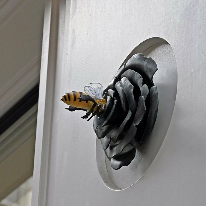3D street art of a bee interacting with a flower sculpture, showcasing clever interpretations of public spaces through street art.