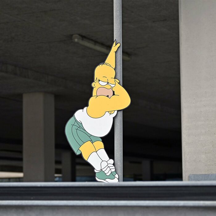 Street art interpretation showing a cartoon character interacting creatively with a public space pole.