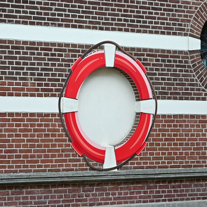 Street art depicting a red life preserver painted on a brick wall as a clever public space interpretation.