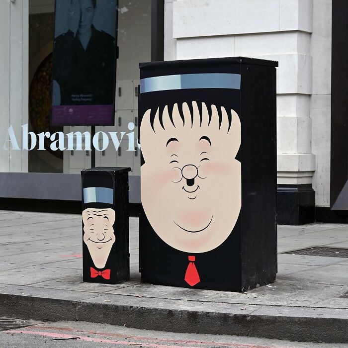 Street art on utility boxes showing smiling faces with bow tie and tie, creatively transforming public spaces.