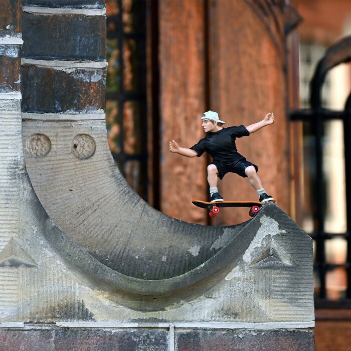 Miniature skateboarder on an urban stone structure, showcasing clever street art interpretations of public spaces by Frankey.